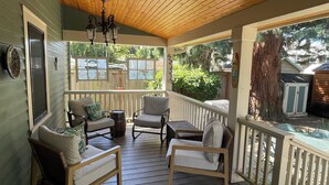 A covered porch with wooden flooring, two chairs with cushions, a small table, and a hanging light fixture. - Gorgeous 3 bed/ 2 bath home in the heart of Sellwood! Walk to everything! (Portland)