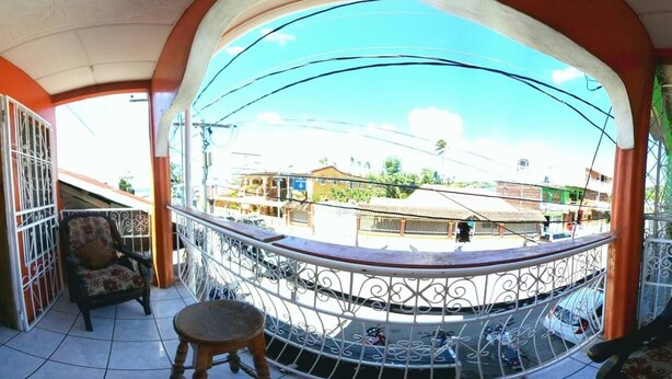 A balcony with a metal railing, a chair, and a small stool. - Hostal Brisas y Olas - Hostel (San Juan del Sur)