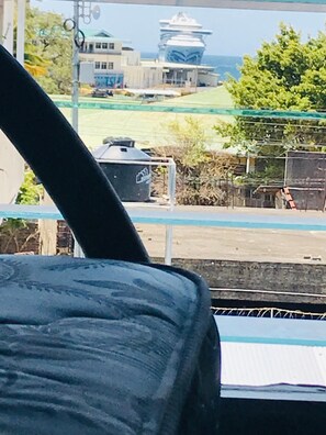 A view from a window with a metal railing, overlooking a beach with a building in the background. - Hostal Brisas y Olas - Hostel (San Juan del Sur)