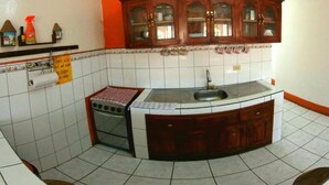 A kitchen with a curved island, a stove, and a sink. - Hostal Brisas y Olas - Hostel (San Juan del Sur)