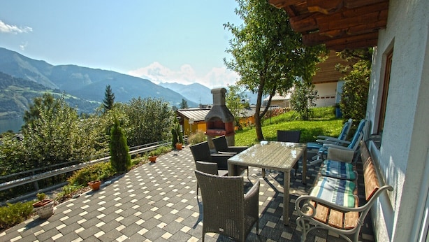 Un patio al aire libre con una mesa y sillas, una chimenea de piedra y vistas a montañas.