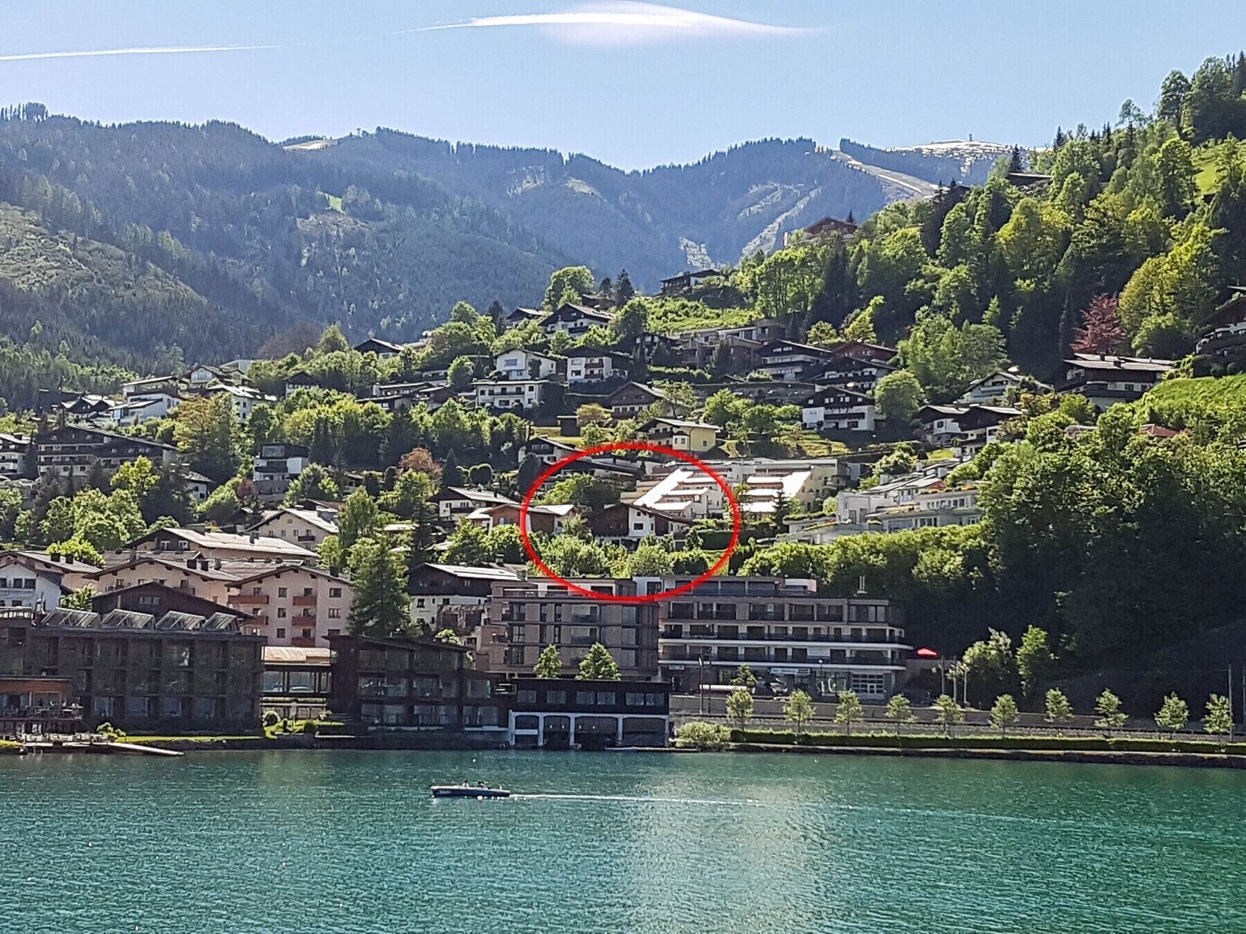 A lakeside town with buildings along the shore and a boat on the water.