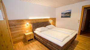 Un dormitorio con cabecera de madera, una mesita de noche y una cama con ropa blanca.
