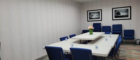 A conference room with a long table, blue chairs, and framed pictures on the wall.