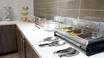 Montaje tipo bufé con un tostador, una cesta de pan y diversas opciones de comida.