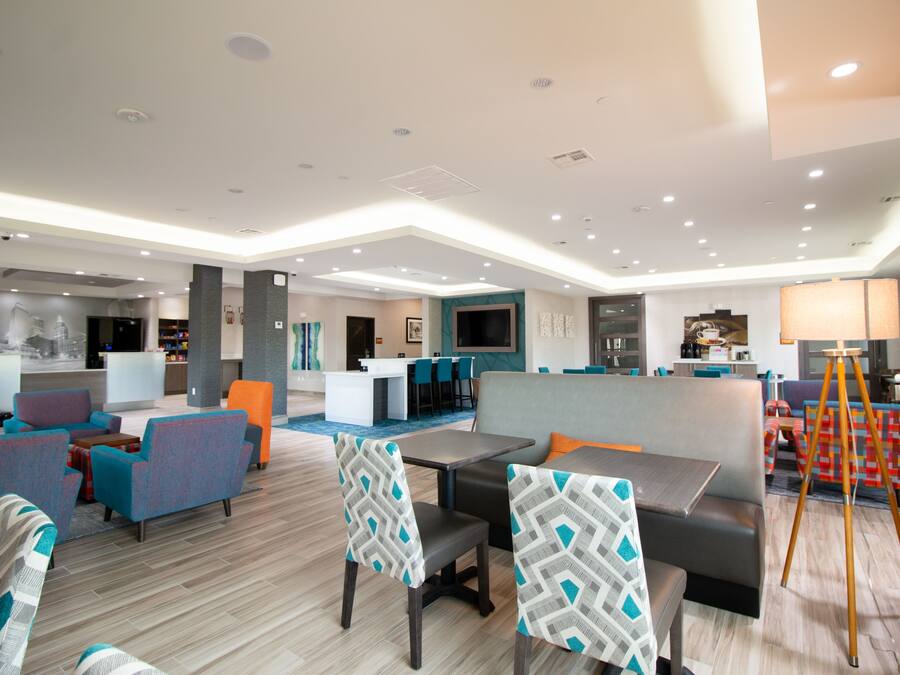 A modern hotel lobby with seating areas, a bar, and a dining space.