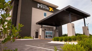 A modern hotel building with a prominent entrance and a covered waiting area. - Hotel Pryor (Pryor)