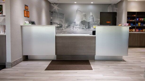 A reception area with a modern design, featuring a reception desk, a digital screen, and a wall mural of a cityscape. - Hotel Pryor (Pryor)