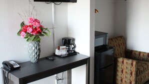 Habitación de hotel con escritorio, televisión, cafetera, bote de basura y sofá estampado.