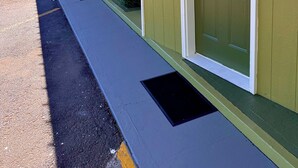 Filas de habitaciones de motel con paredes verdes y detalles blancos, puertas numeradas y un cartel de 'No Fumar' en una de ellas.