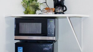 Una kitchenette equipada con microondas, cafetera y un cubo de basura.