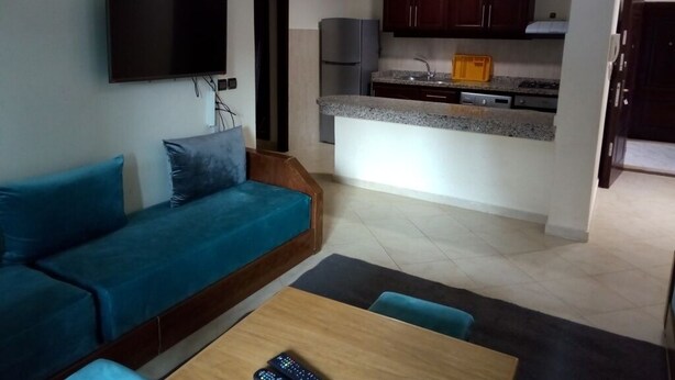 Een woonkamer met een bank, een televisie en een eethoek met een tafel en stoelen.