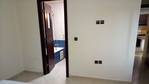 Een kamer met een bed, een deur naar een badkamer en een keukenruimte zichtbaar door een open deur.