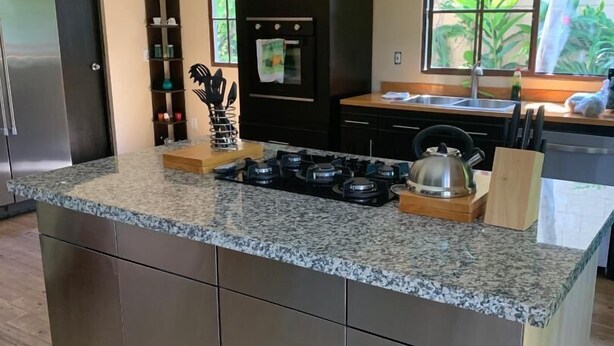 Uma cozinha moderna com bancada de granito, eletrodomésticos de aço inoxidável e uma ilha grande.