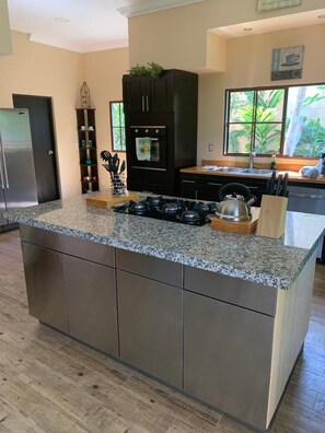 Una cocina moderna con encimera de granito, electrodomésticos de acero inoxidable y una isla grande.