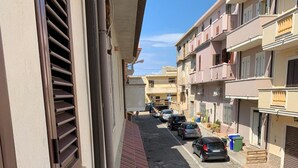A residential street with parked cars, a tiled sidewalk, and multi-story buildings with balconies. - Appartamento Telemaco (Le Castella)