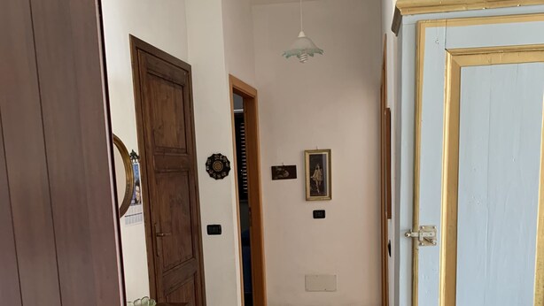 A hallway with a wooden door, a blue door, and a tiled floor. - Appartamento Telemaco (Le Castella)