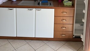 A kitchen with white cabinets, a stainless steel sink, and a wooden countertop. - Appartamento Telemaco (Le Castella)
