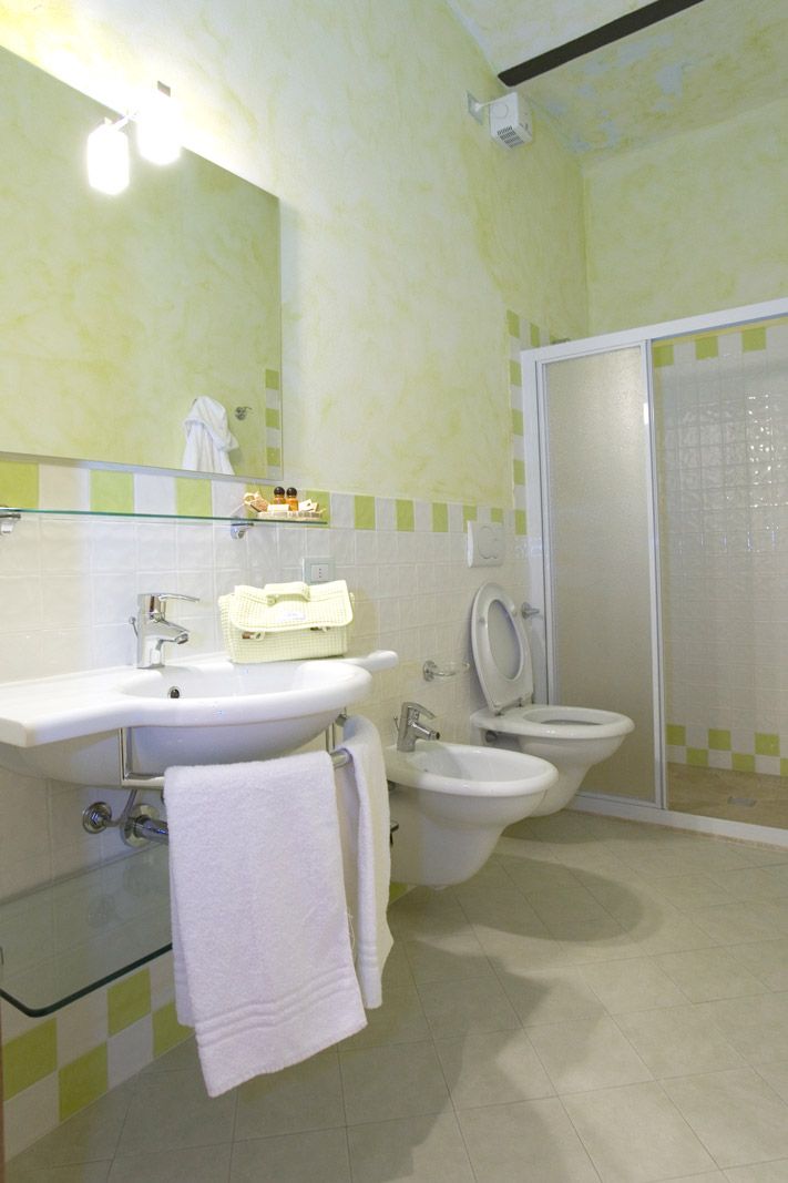 A bathroom with a sink, two toilets, a glass shower enclosure, and a mirror.