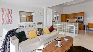 A modern living room with a sofa, coffee table, and a kitchen area in the background. - Ocean Villas-Villa Sol (Guia)