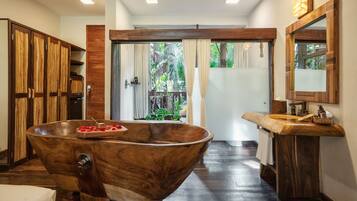 A modern bathroom with a large wooden bathtub, wooden cabinets, and a wooden vanity with a mirror.
