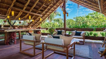 An outdoor seating area with wooden furniture and a thatched roof.