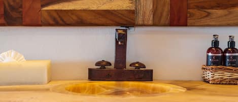 A wooden vanity with a marble countertop, a mirror, a soap dish, and two bottles of hand soap.