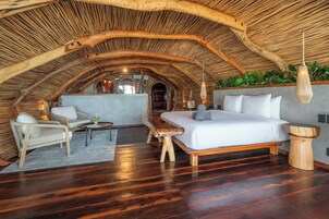 Un dormitorio en el ático con techo de madera, una cama, un sofá y una pequeña mesa.