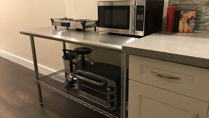A kitchen with a microwave, toaster, and coffee maker on a countertop, and a built-in oven below. - DaLight - A beautiful home in a quiet neighborhood (Kailua)