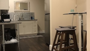 A modern kitchen with dark wood flooring, a stainless steel refrigerator, and a bar stool. - DaLight - A beautiful home in a quiet neighborhood (Kailua)
