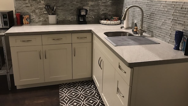 A kitchen with white cabinets, a granite countertop, a sink with a modern faucet, and a patterned backsplash. - DaLight - A beautiful home in a quiet neighborhood (Kailua)