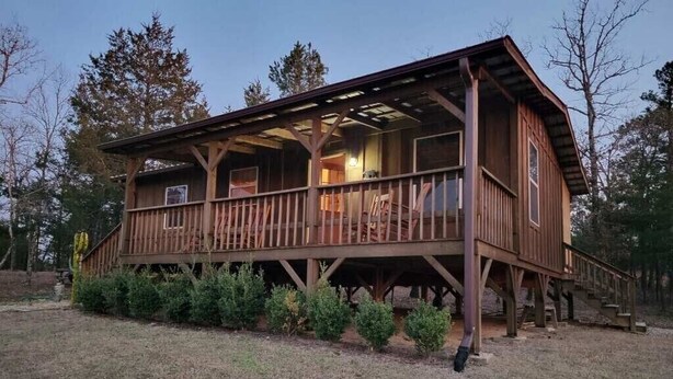 A wooden cabin with a porch, multiple windows, and a covered deck area. - BIG BUCK CABIN  (Rattan)