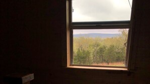 A room with a window overlooking a forested area. - BIG BUCK CABIN  (Rattan)