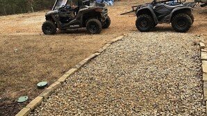 Two ATVs parked on a gravel path with a wooden border, surrounded by dry grass and trees. - BIG BUCK CABIN  (Rattan)