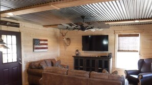 A cozy living room with a sectional sofa, a television, and a mounted deer head. - BIG BUCK CABIN  (Rattan)
