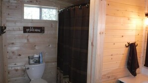 A wooden cabin bathroom with a toilet, a shower curtain, and a towel rack. - BIG BUCK CABIN  (Rattan)