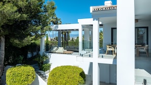 Ein modernes Haus mit Glasbalkon, weißer Fassade und Blick auf die Landschaft.
