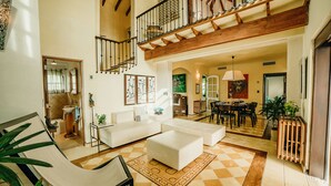 Uma sala de estar ampla com teto alto, escada e área de jantar.