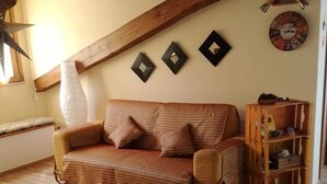 A cozy room with a wooden ceiling, a striped sofa, a small wooden shelf, and a wall clock. - Superb Mansarda ... (Caserta)