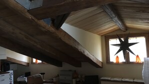 A loft-style room with exposed wooden beams, a large star decoration, a sofa, a table, and a window with curtains. - Superb Mansarda ... (Caserta)