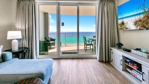 A hotel room with a bed, a desk, a chair, a TV, and a balcony with a view of the ocean. - 🏖️Gulf Front-Free Beach Chairs-2BR Twin Palms 1401🏖️ (Panama City Beach)