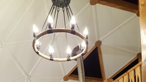 Et værelse med højt til loftet, træpaneler, en pejs og en moderne lysekrone.