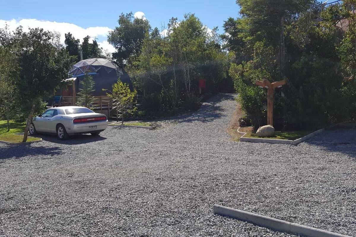 A gravel driveway leading to a building with a dome-like structure.