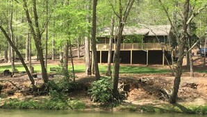 A cabin with a deck overlooking a river, surrounded by trees. - Chestatee River Cabin (Dahlonega)