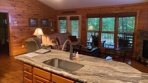 A cabin interior with a kitchen, dining area, and a fireplace. - Chestatee River Cabin (Dahlonega)