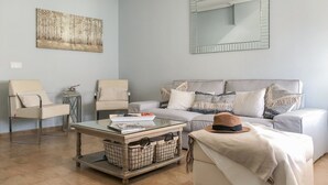 Un salon comprenant un canapé, deux fauteuils, une table basse et un grand miroir.