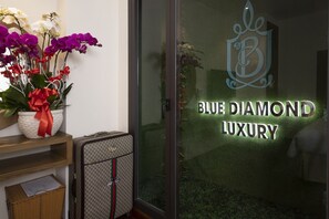 Entrada de un lujoso hotel boutique con puerta de cristal que muestra el nombre "Blue Diamond Luxury".