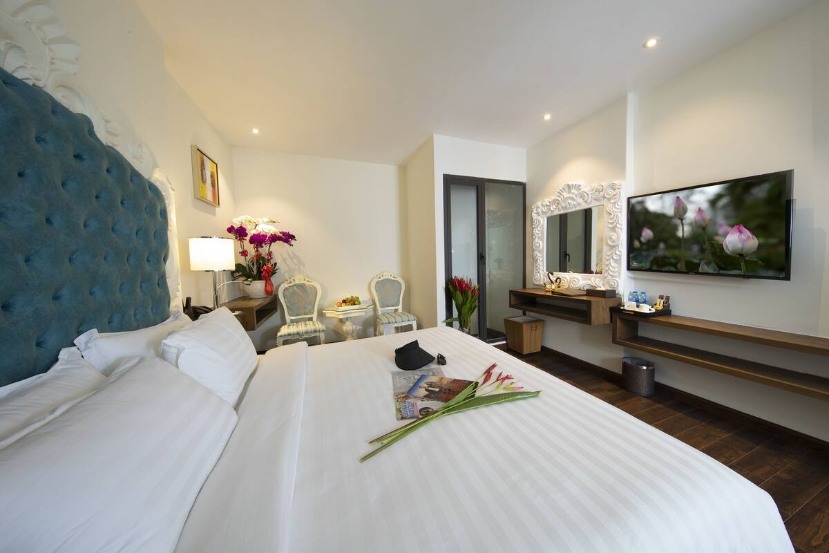 Een hotelkamer met een groot bed, een televisie, een bureau met een lamp en een spiegel.