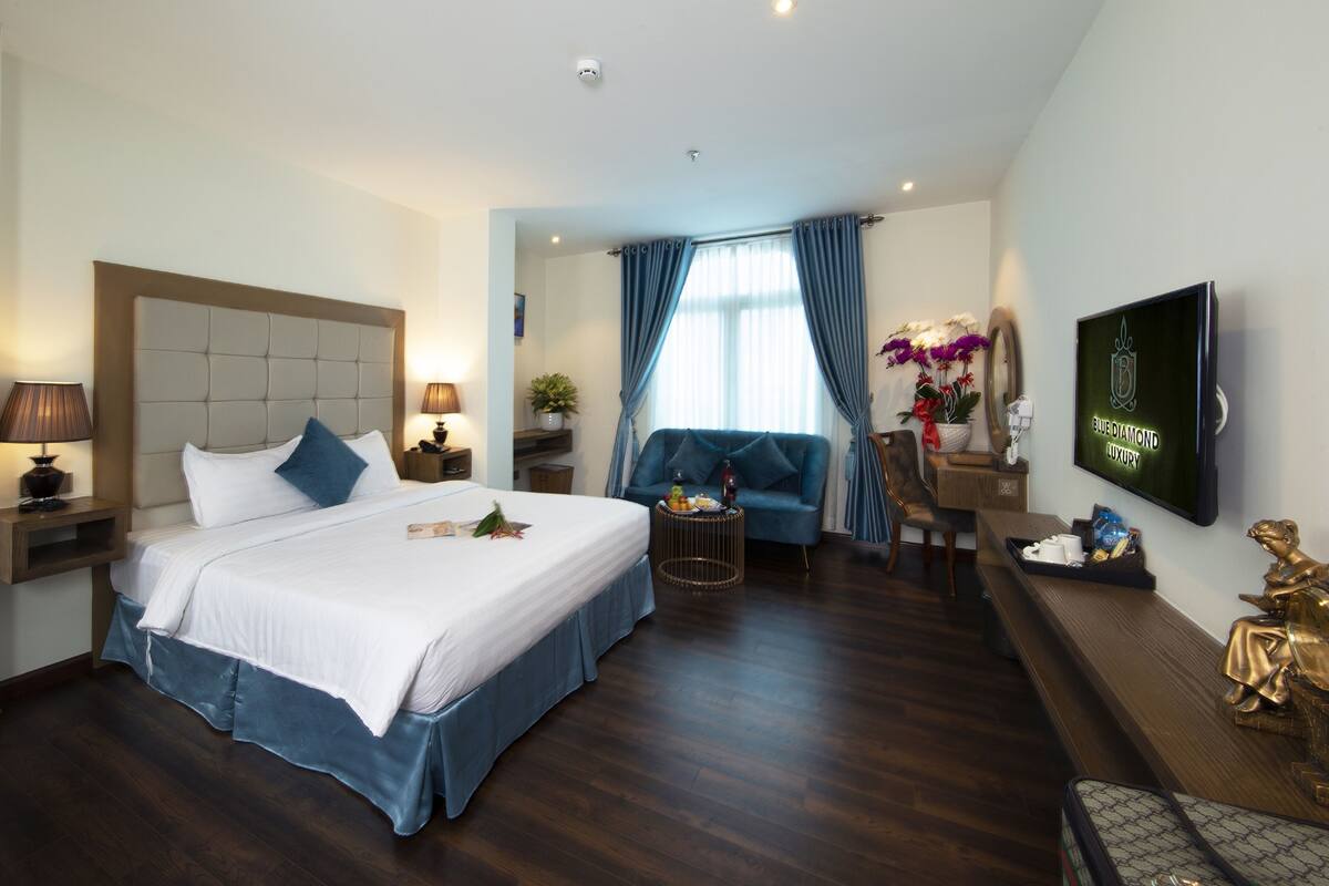 Een hotelkamer met een groot bed, een bank, een televisie en een bureau met een computer.