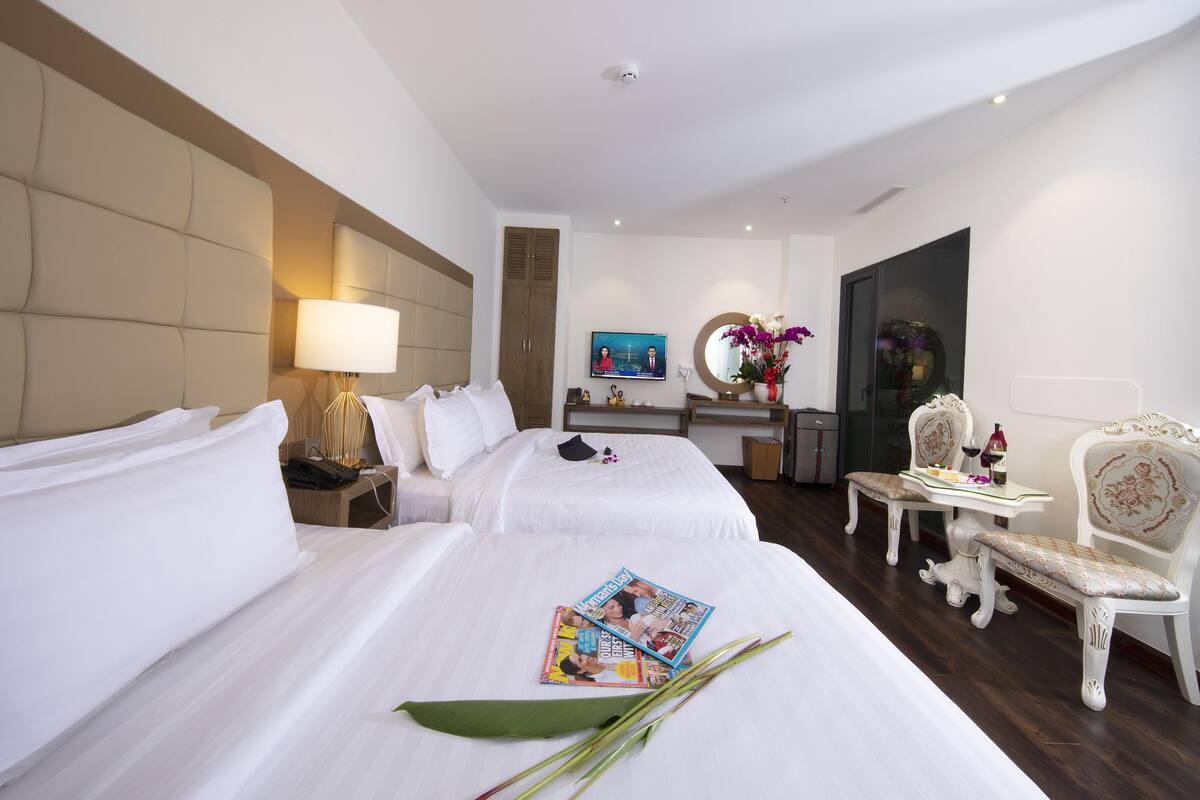 Een hotelkamer met twee bedden, een zithoek met een tafel en stoelen, een spiegel en een televisie.